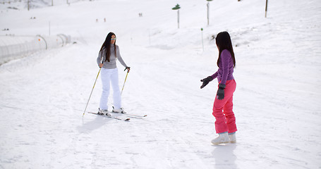 Image showing Young woman learning to ski from a friend