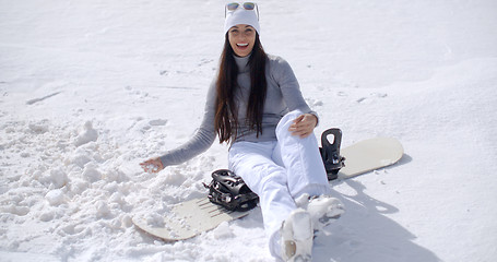 Image showing Attractive young woman sitting on her snowboard