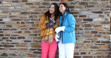 Image showing Cute twins in winter coats leaning on wall