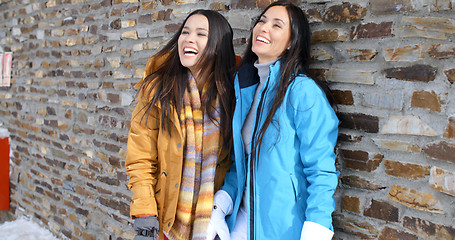 Image showing Laughing twins in jackets and glove near wall