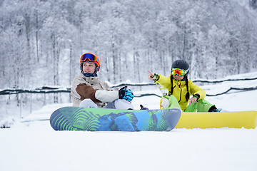 Image showing Two snowboarders - men and women sitting in the mountains