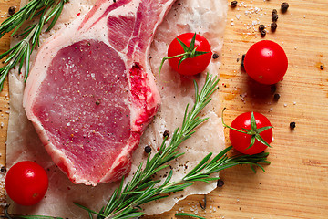 Image showing Pieces of crude meat with rosemary and tomatoes.