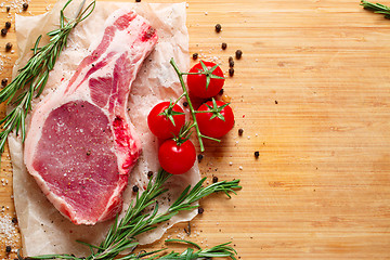 Image showing Pieces of crude meat with rosemary and tomatoes.