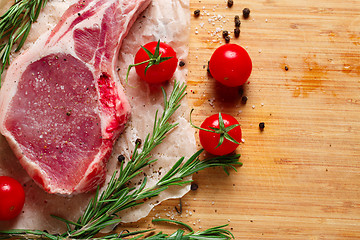 Image showing Pieces of crude meat with rosemary and tomatoes.