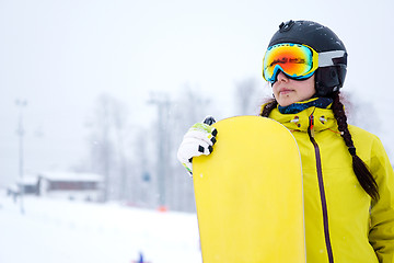 Image showing Female snowboarder standing with snowboard