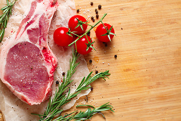 Image showing Pieces of crude meat with rosemary and tomatoes.