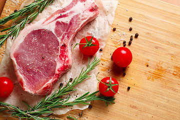 Image showing Pieces of crude meat with rosemary and tomatoes.