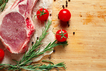 Image showing Pieces of crude meat with rosemary and tomatoes.