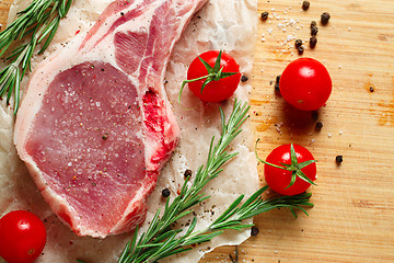 Image showing Pieces of crude meat with rosemary and tomatoes.