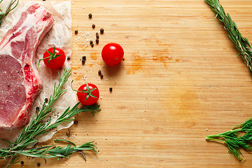 Image showing Pieces of crude meat with rosemary and tomatoes.