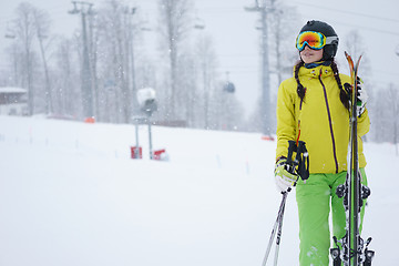 Image showing Female skier standing with skies in one hand on background beautiful mountain landscape