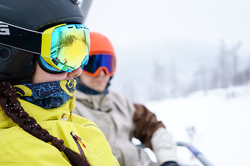 Image showing Couple sitting on chairlift in mountain resorts.