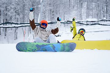 Image showing Two snowboarders - men and women sitting in the mountains