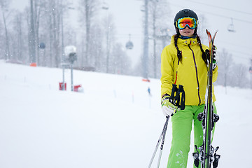 Image showing Female skier standing with skies in one hand on background beautiful mountain landscape