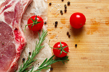 Image showing Pieces of crude meat with rosemary and tomatoes.