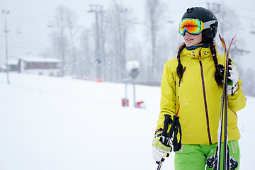 Image showing Female skier standing with skies in one hand on background beautiful mountain landscape