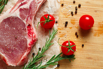 Image showing Pieces of crude meat with rosemary and tomatoes.