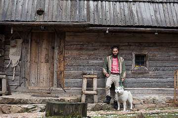 Image showing hipster with dog in front of wooden house