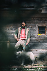 Image showing hipster with dog in front of wooden house