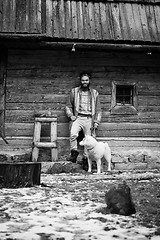 Image showing hipster with dog in front of wooden house