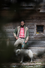 Image showing hipster with dog in front of wooden house