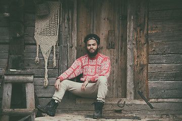 Image showing portrait of young hipster in front of wooden house