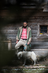 Image showing hipster with dog in front of wooden house