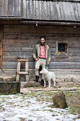 Image showing hipster with dog in front of wooden house