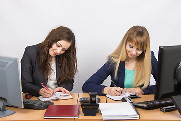 Image showing Two business women working in the office with one desk