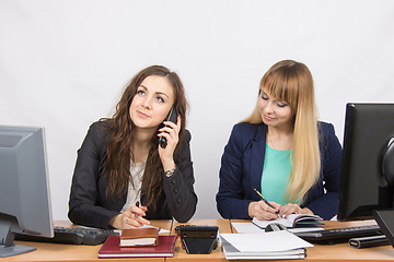 Image showing Young girls in the office, another talking on the phone, the other writes in diary