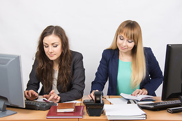 Image showing Two young business women working in the office at the workplace at the same table