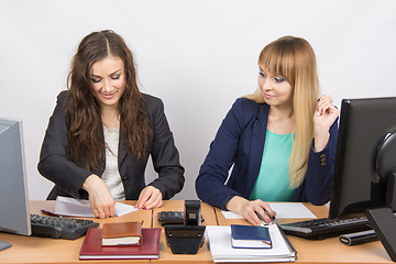 Image showing Two young women working in the office, one puts a piece of paper, the second in amazement staring at her