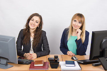 Image showing Two young girls sitting at a table in the office and looking at the frame