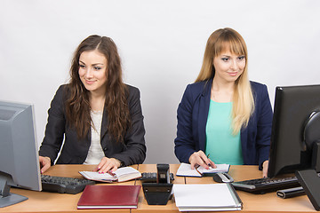 Image showing Two business women working in the office with one desk