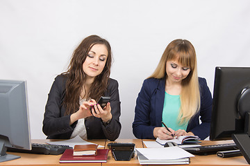 Image showing Young girls in the office, one dials a phone number, the second writes in diary