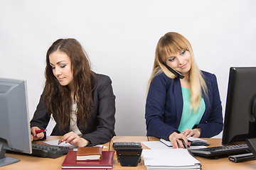 Image showing Young girls in the office, one works in the computer, the other on the phone and looking at the screen