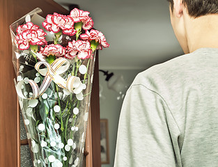 Image showing A young man with a bouquet of flowers in his hands.