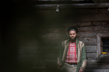 Image showing portrait of young hipster in front of wooden house