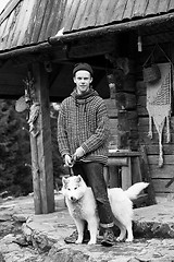 Image showing young hipster with dog in front of wooden house