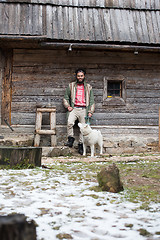 Image showing hipster with dog in front of wooden house