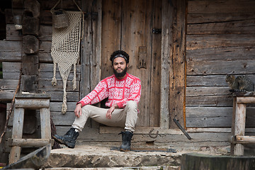 Image showing portrait of young hipster in front of wooden house