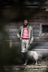 Image showing hipster with dog in front of wooden house