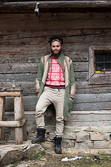 Image showing portrait of young hipster in front of wooden house