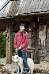 Image showing young hipster with dog in front of wooden house