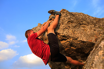 Image showing Young man climbing on a wall