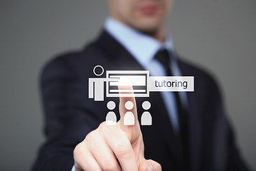 Image showing Businessman pressing button on touch screen interface and select Tutoring. Business concept.