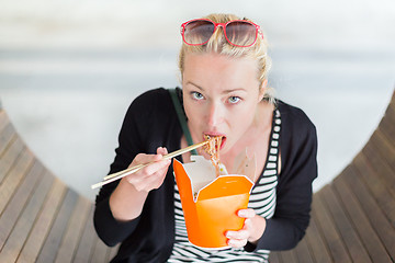 Image showing Woman eating Chinese take-away noodels.