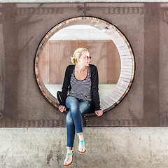 Image showing Young urban woman sitting in city park.