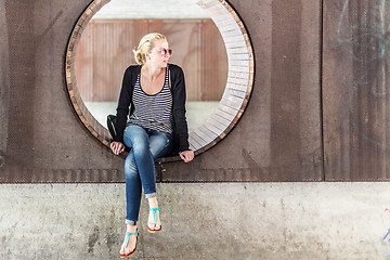 Image showing Young urban woman sitting in city park.