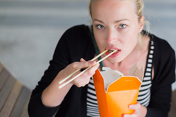 Image showing Woman eating Chinese take-away noodels.